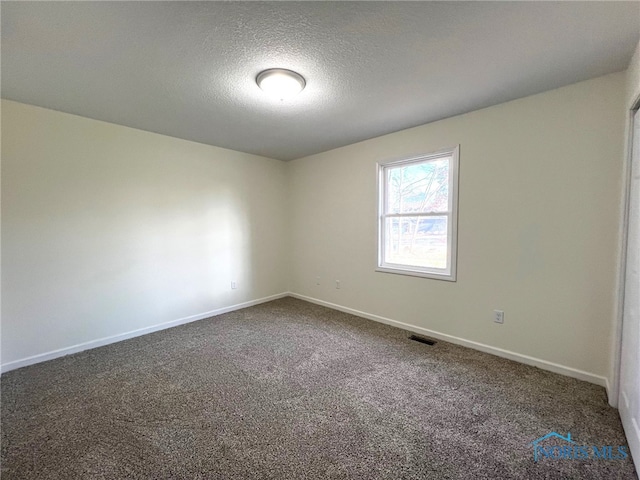 carpeted spare room featuring a textured ceiling