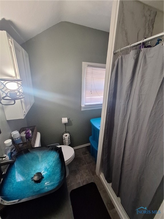 bathroom featuring curtained shower, tile patterned flooring, vaulted ceiling, and toilet