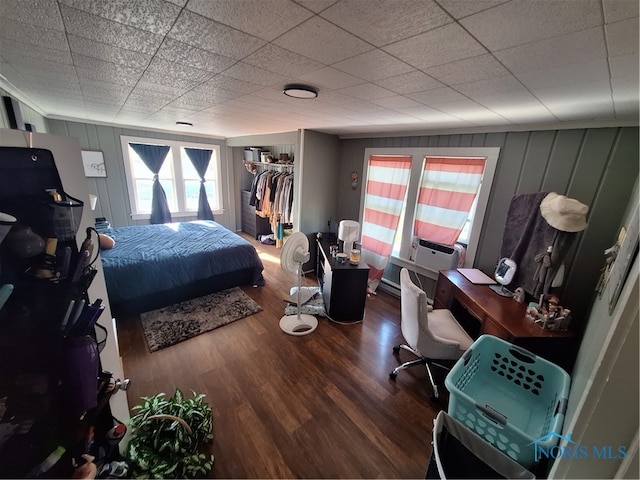 bedroom with hardwood / wood-style flooring, a closet, a drop ceiling, and a walk in closet