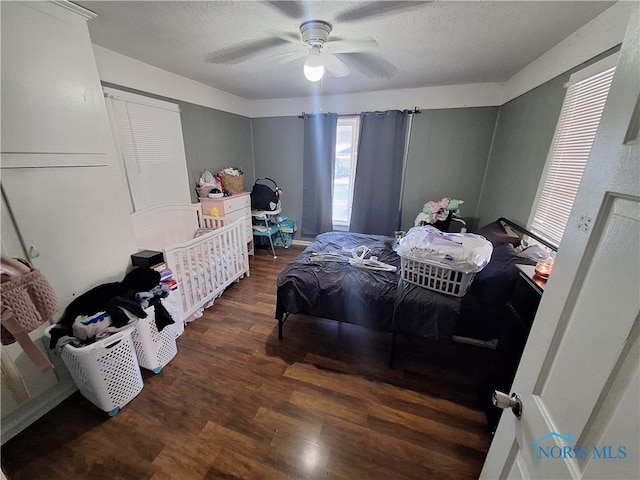 bedroom featuring ceiling fan, dark hardwood / wood-style floors, and a textured ceiling