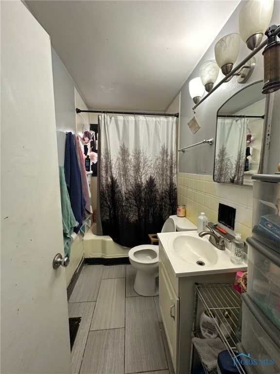 full bathroom featuring vanity, tasteful backsplash, shower / bath combo with shower curtain, tile walls, and toilet