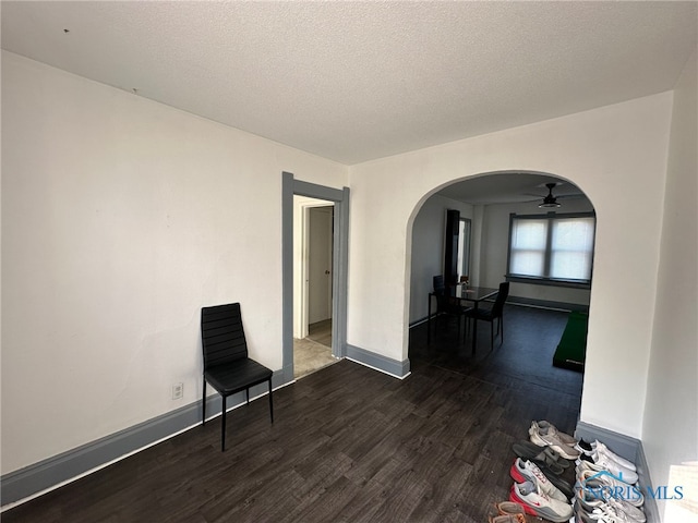 interior space featuring a textured ceiling, ceiling fan, and dark wood-type flooring