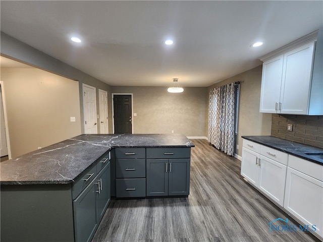 kitchen with white cabinets, tasteful backsplash, gray cabinetry, dark stone counters, and hardwood / wood-style floors