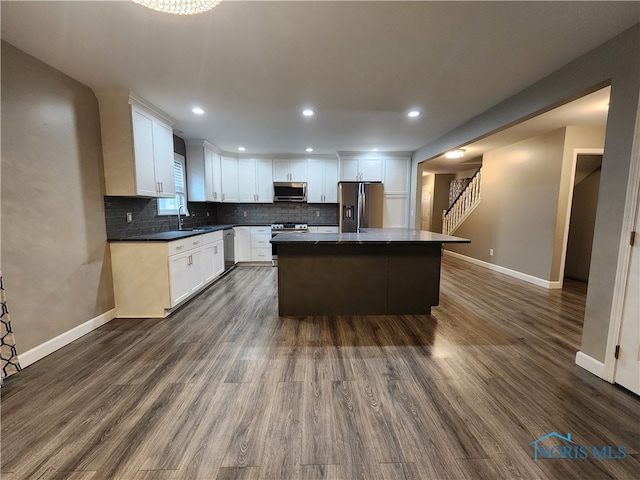 kitchen featuring a center island, dark wood-type flooring, sink, white cabinets, and appliances with stainless steel finishes