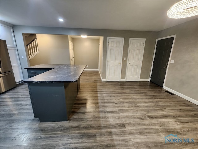 kitchen featuring dark hardwood / wood-style flooring, a chandelier, a center island, and stainless steel refrigerator