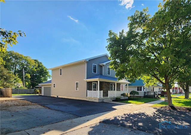 view of property with a front lawn, covered porch, and a garage