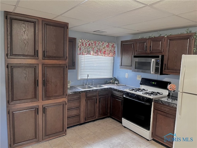 kitchen featuring a paneled ceiling, white appliances, dark brown cabinetry, and sink