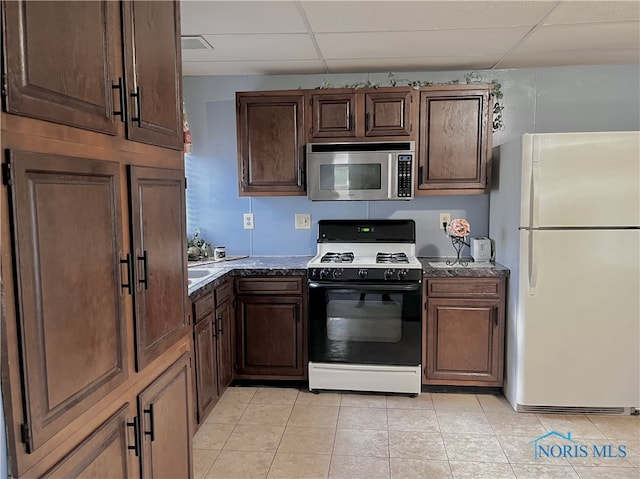 kitchen with a drop ceiling, light tile patterned floors, and white appliances