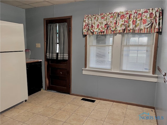 interior space with a paneled ceiling and light tile patterned floors