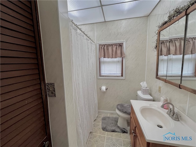 bathroom with vanity, walk in shower, tile walls, tile patterned floors, and toilet