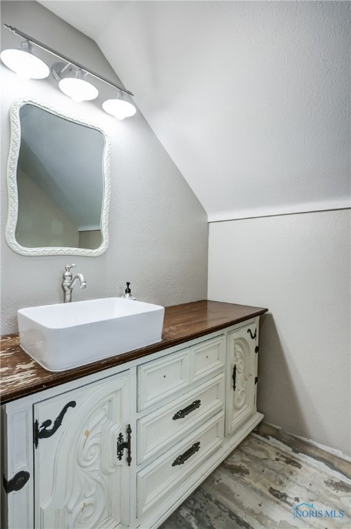 bathroom featuring vanity, hardwood / wood-style floors, and vaulted ceiling