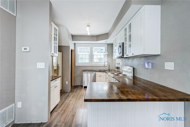 2915 N 109th St, Toledo, OH 43611 - kitchen with appliances with stainless steel finishes, wood finished floors, glass insert cabinets, white cabinets, and a peninsula