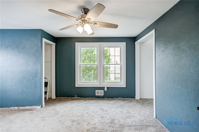 carpeted spare room featuring ceiling fan