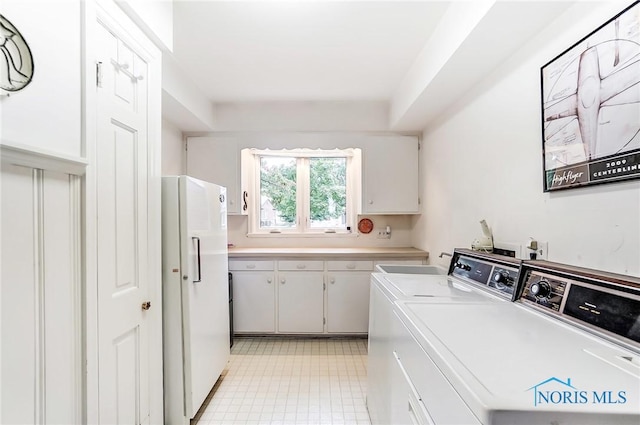 clothes washing area featuring cabinets and washing machine and clothes dryer