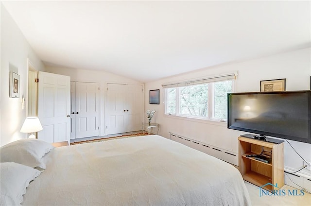 unfurnished bedroom featuring lofted ceiling, baseboard heating, and multiple closets