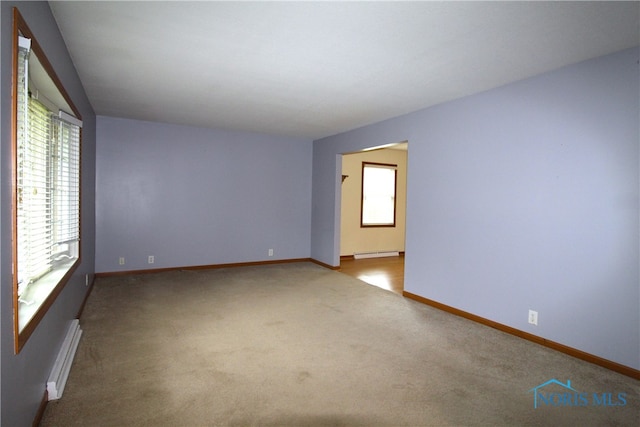 unfurnished room with light carpet, a baseboard radiator, and a healthy amount of sunlight