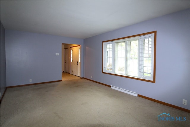 carpeted spare room with a baseboard heating unit