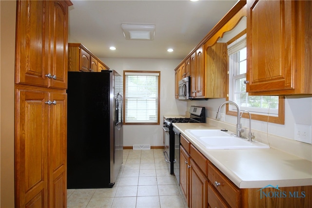 kitchen featuring appliances with stainless steel finishes, sink, and light tile patterned floors