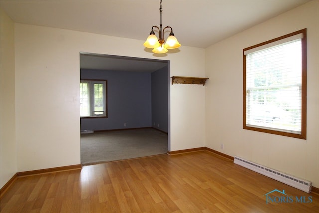 spare room with a notable chandelier, a baseboard radiator, and wood-type flooring