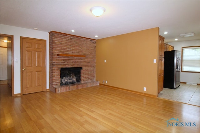 unfurnished living room with a fireplace and light wood-type flooring