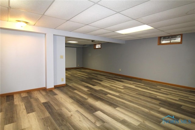 basement with dark hardwood / wood-style flooring and a paneled ceiling