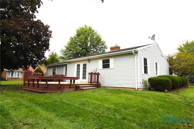 rear view of house featuring a wooden deck and a lawn