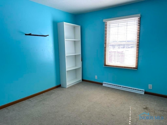 carpeted empty room with a baseboard heating unit