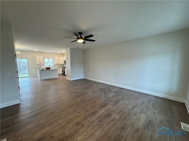 unfurnished living room with ceiling fan and dark wood-type flooring