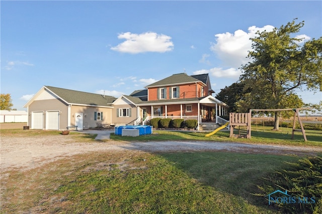 rear view of property with covered porch, a yard, and a playground