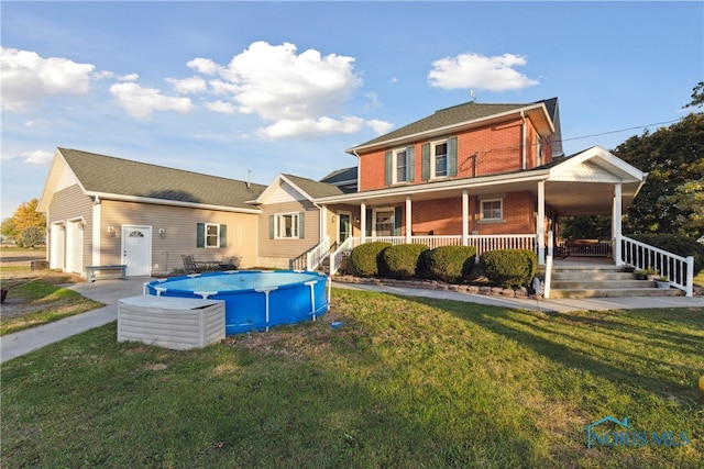 rear view of property featuring a yard, a porch, and a garage