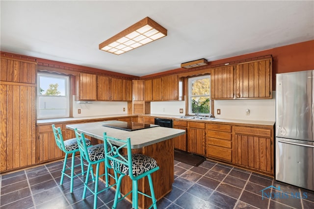 kitchen with black appliances, sink, a kitchen bar, and a kitchen island