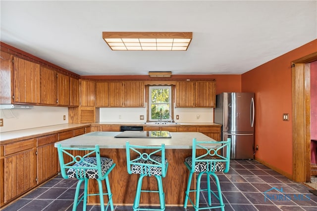 kitchen with a center island, a kitchen bar, and stainless steel fridge