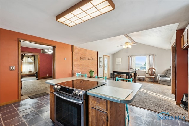 kitchen with ceiling fan, stainless steel range with electric stovetop, lofted ceiling, and dark carpet