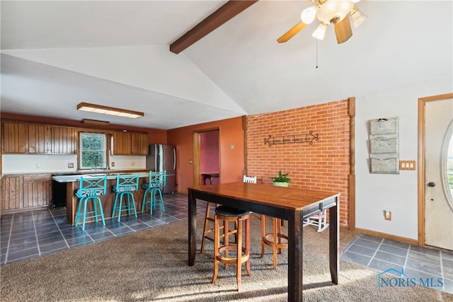 carpeted dining room with sink, vaulted ceiling with beams, and ceiling fan