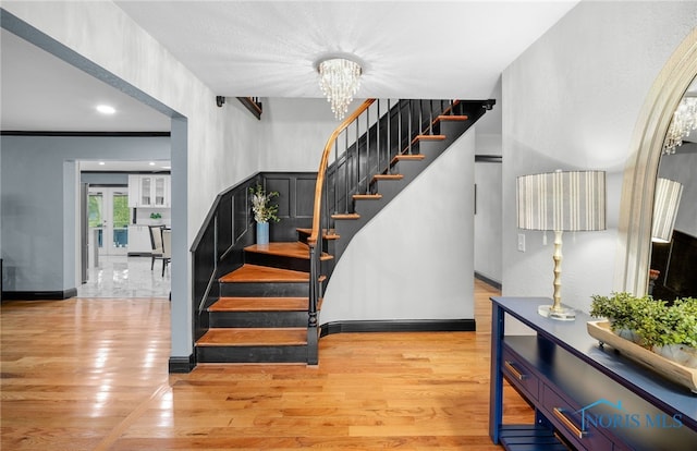 stairway featuring wood-type flooring and a notable chandelier