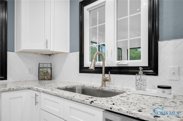 kitchen featuring light stone countertops, sink, decorative backsplash, and white cabinetry