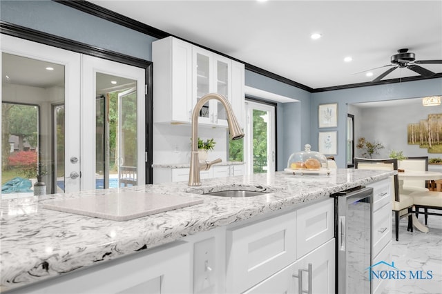 kitchen featuring white cabinets, ceiling fan, beverage cooler, and sink