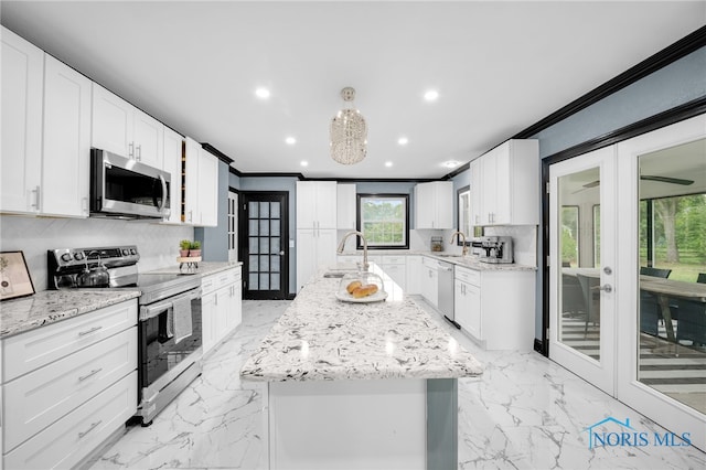 kitchen featuring appliances with stainless steel finishes, white cabinets, french doors, a kitchen island with sink, and sink