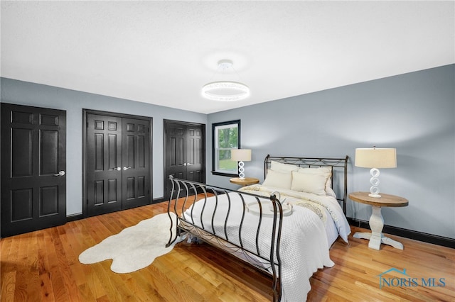 bedroom with light hardwood / wood-style floors and multiple closets