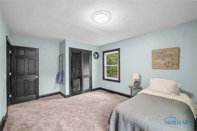 bedroom featuring a closet, a textured ceiling, and carpet flooring