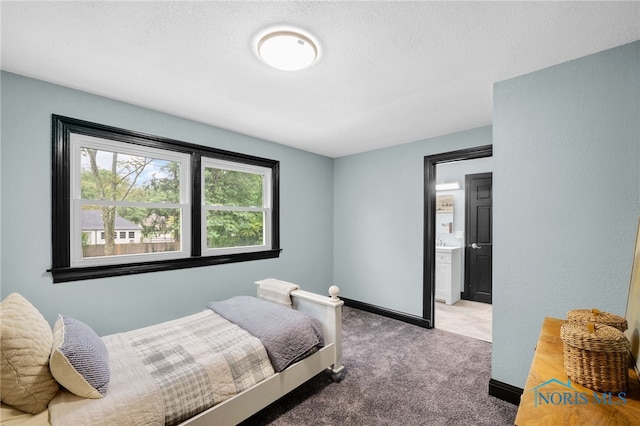 bedroom featuring a textured ceiling, carpet flooring, and ensuite bath