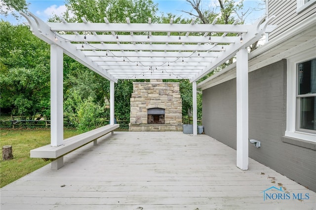 wooden deck featuring a pergola and an outdoor stone fireplace