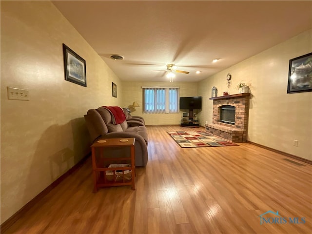 living room with a brick fireplace, ceiling fan, and hardwood / wood-style floors