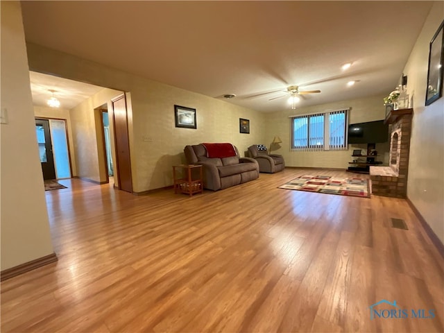 unfurnished living room with hardwood / wood-style floors, ceiling fan, a brick fireplace, and plenty of natural light