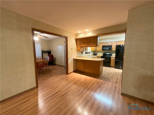 kitchen with kitchen peninsula, black appliances, light hardwood / wood-style floors, and ceiling fan