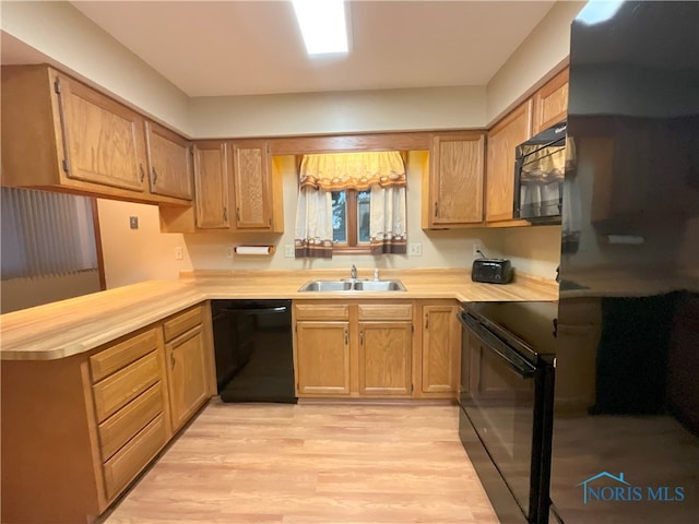 kitchen featuring light hardwood / wood-style flooring, black appliances, kitchen peninsula, and sink