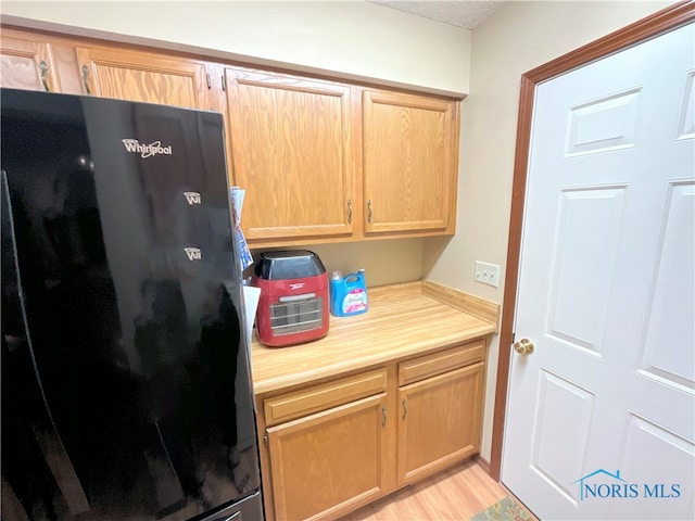 kitchen with light hardwood / wood-style flooring and black refrigerator