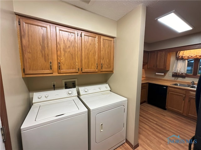 laundry area with cabinets, a textured ceiling, sink, light hardwood / wood-style flooring, and separate washer and dryer