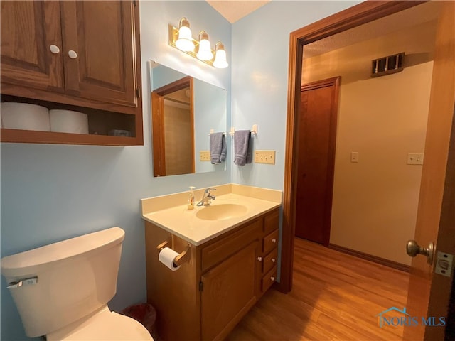 bathroom with hardwood / wood-style flooring, vanity, and toilet