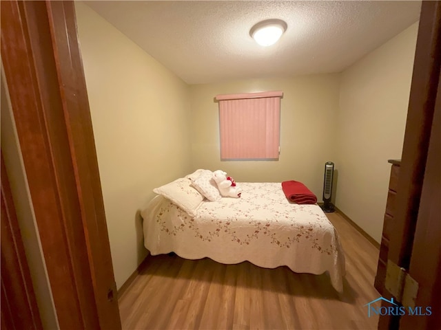 bedroom with a textured ceiling and light hardwood / wood-style floors